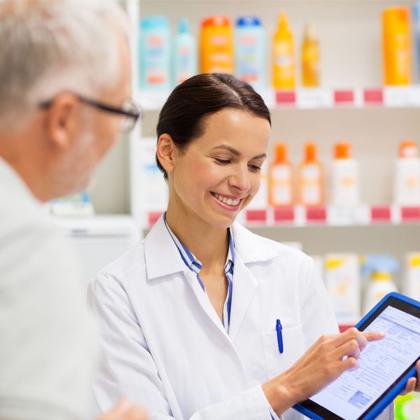 medicine, pharmaceutics, healthcare and technology concept - happy apothecary and senior customer with tablet pc computer at pharmacy